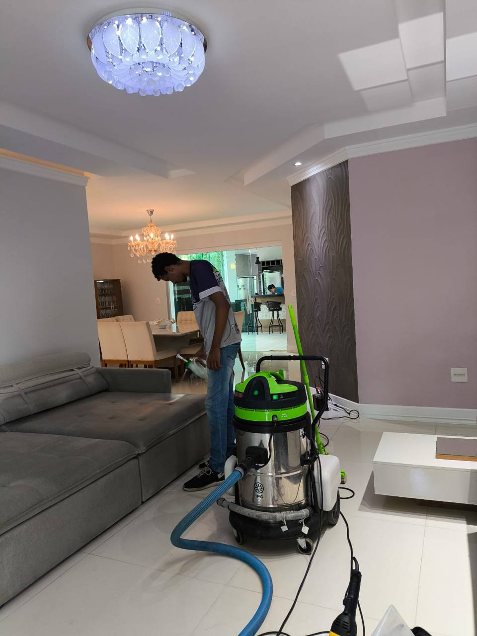 Profissional da Mac Clean preparando o atendimento em sala residencial ampla, ao lado da máquina profissional verde