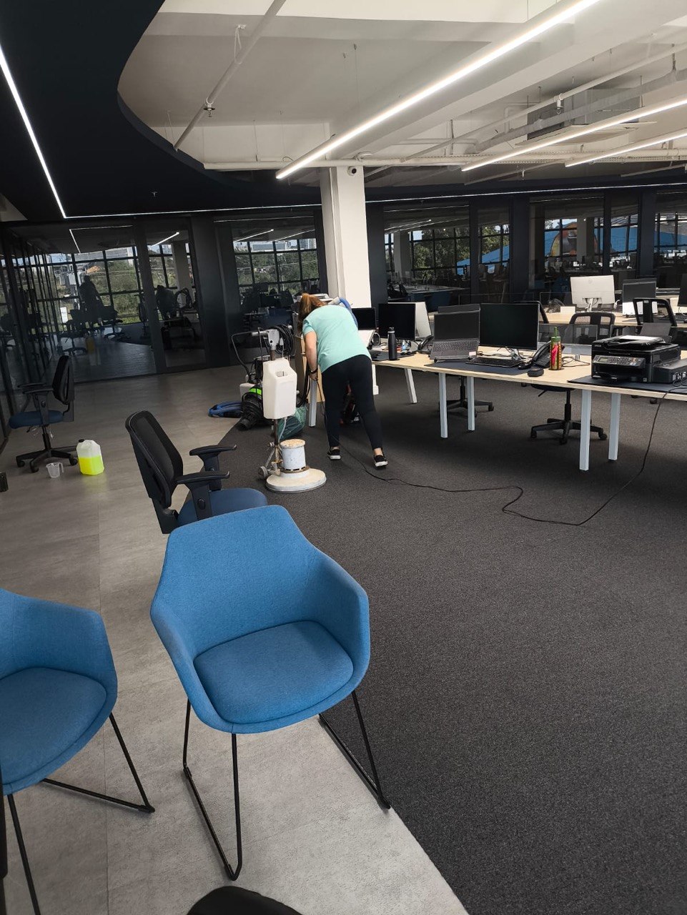 Higienização de carpete em escritório amplo, com estações de trabalho e vista externa